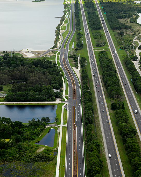 Aerial view of a highway with a lake on the left side